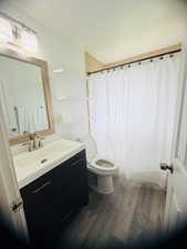 Full bath with vanity, dark wood-style floors, and shower / bath combination with curtain