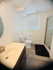 Full bath featuring vanity, a stall shower, and dark wood-style floors
