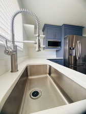 Kitchen view of blue cabinets, stainless steel appliances, and open shelves