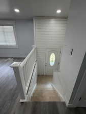 Stairway with wood finished floors and recessed lighting