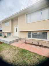 View of front facade with stucco siding, a patio, and a front lawn