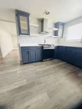Kitchen featuring blue cabinetry, glass insert cabinets, open shelves, stainless steel stove, and a textured ceiling