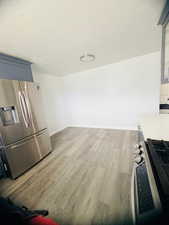 Kitchen with stainless steel appliances, dark wood finished floors, a textured ceiling, glass fronted cabinets, and blue cabinets