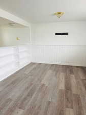 Unfurnished room featuring wood finished floors, a textured ceiling, and a wainscoted wall