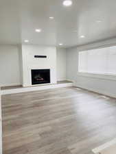 Unfurnished living room featuring a fireplace, light wood-style flooring, and recessed lighting