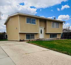 Split foyer home with stucco siding and a front yard