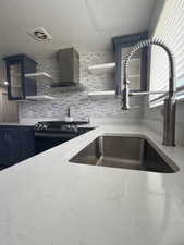 Kitchen with light stone countertops, open shelves, glass insert cabinets, stainless steel range with gas cooktop, and decorative backsplash