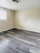 Spare room featuring dark wood finished floors and baseboards