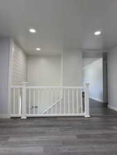 Corridor featuring dark wood-style floors, recessed lighting, and an upstairs landing