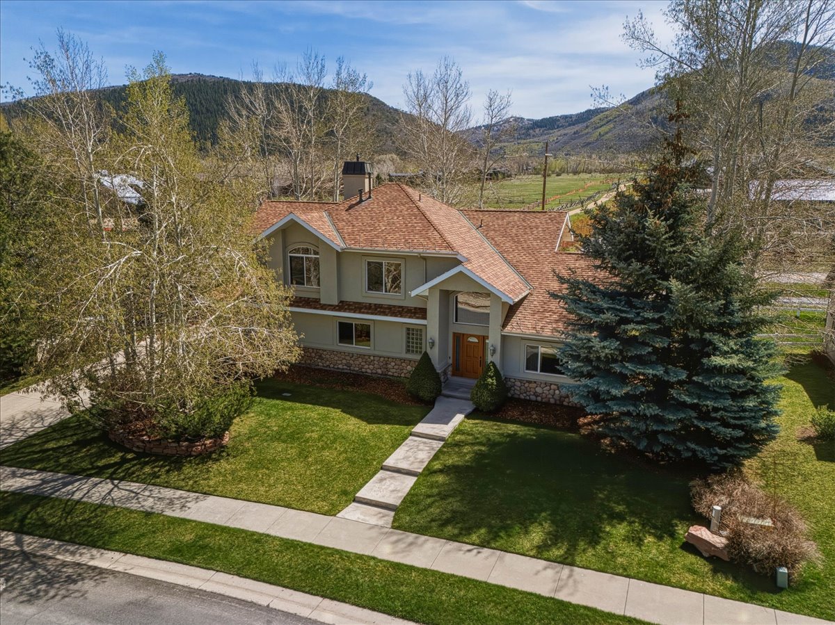 View of front of home featuring stucco siding, a front lawn, a mountain view, stone siding, and a chimney