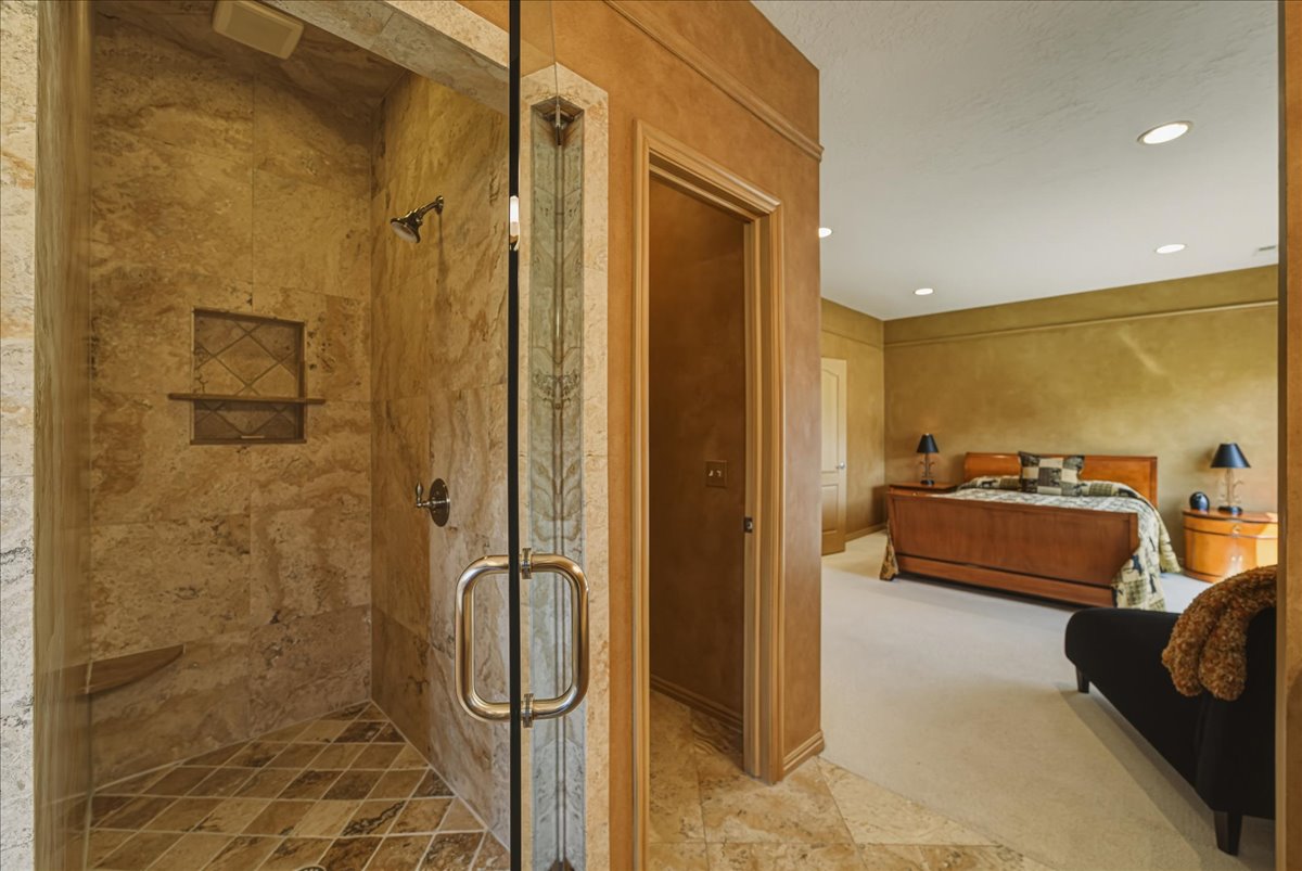 Ensuite bathroom featuring a shower stall, recessed lighting, light colored carpet, and light stone finish floors