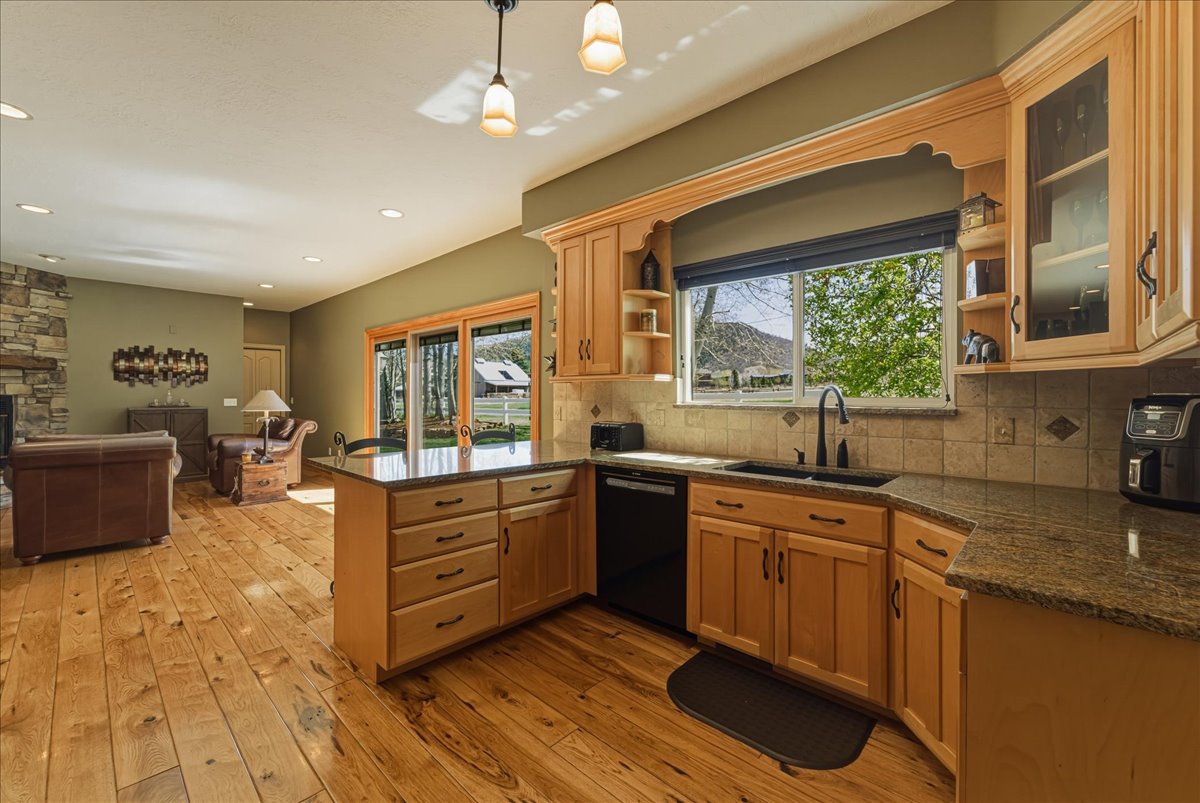Kitchen with a peninsula, open shelves, black dishwasher, and glass fronted cabinets