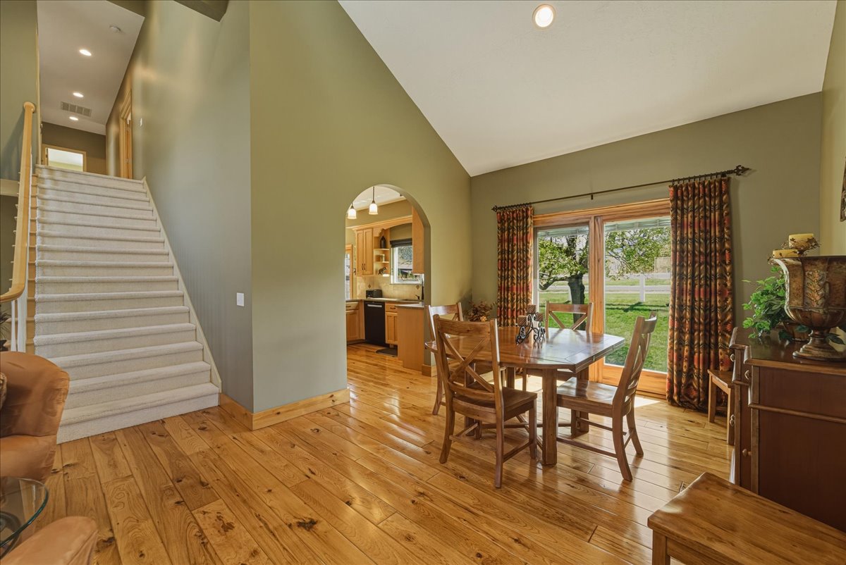 Dining room with arched walkways, light wood-style flooring, lofted ceiling, and recessed lighting