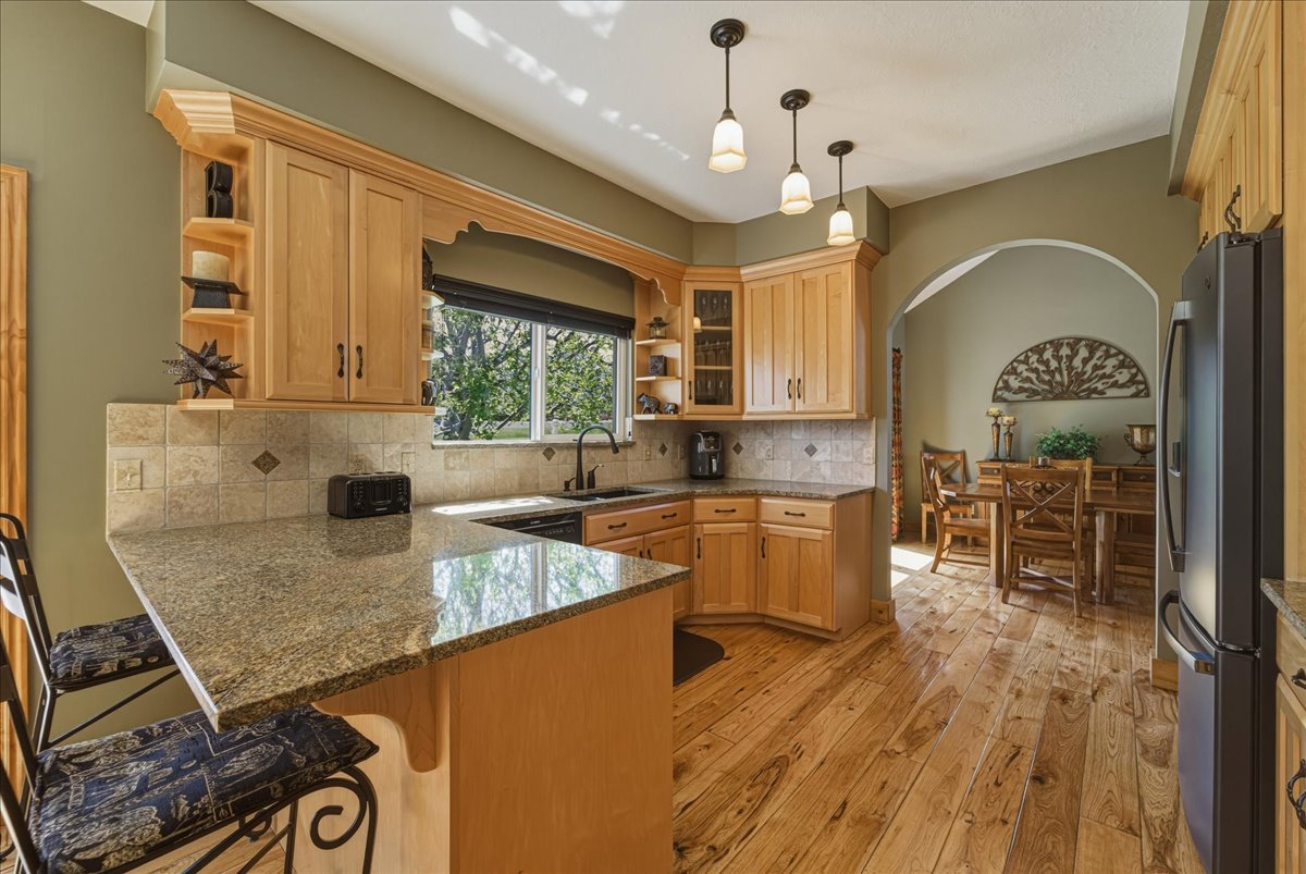 Kitchen featuring a peninsula, open shelves, glass fronted cabinets, a kitchen breakfast bar, and freestanding refrigerator