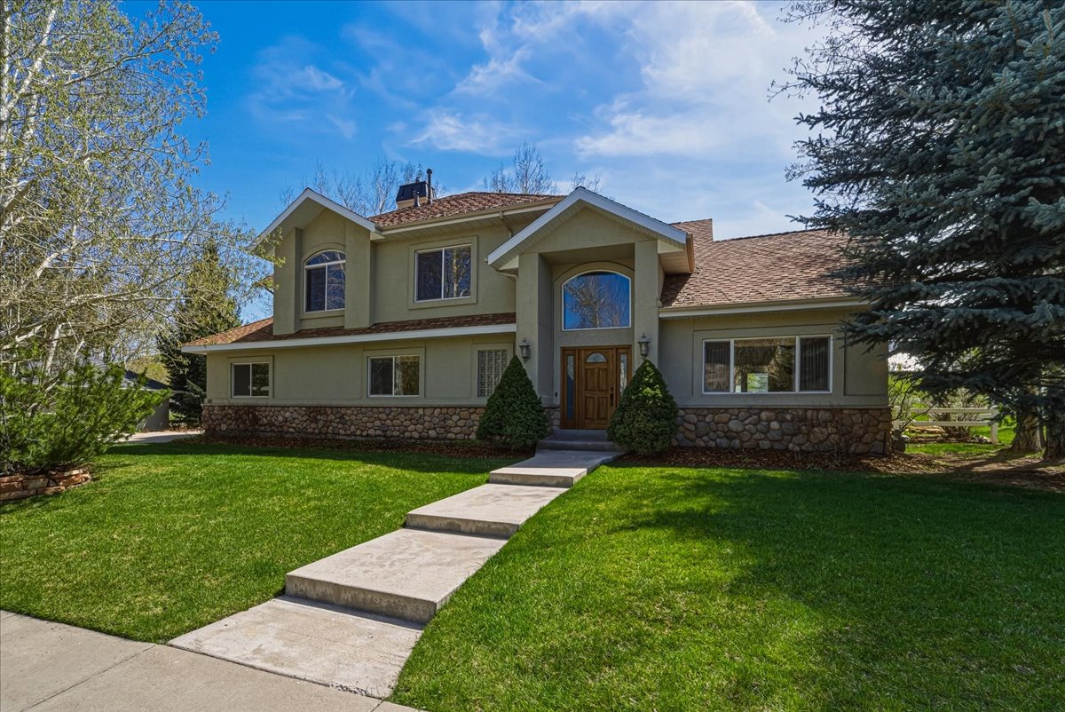 Mediterranean / spanish-style home with stucco siding, stone siding, a front yard, and a chimney