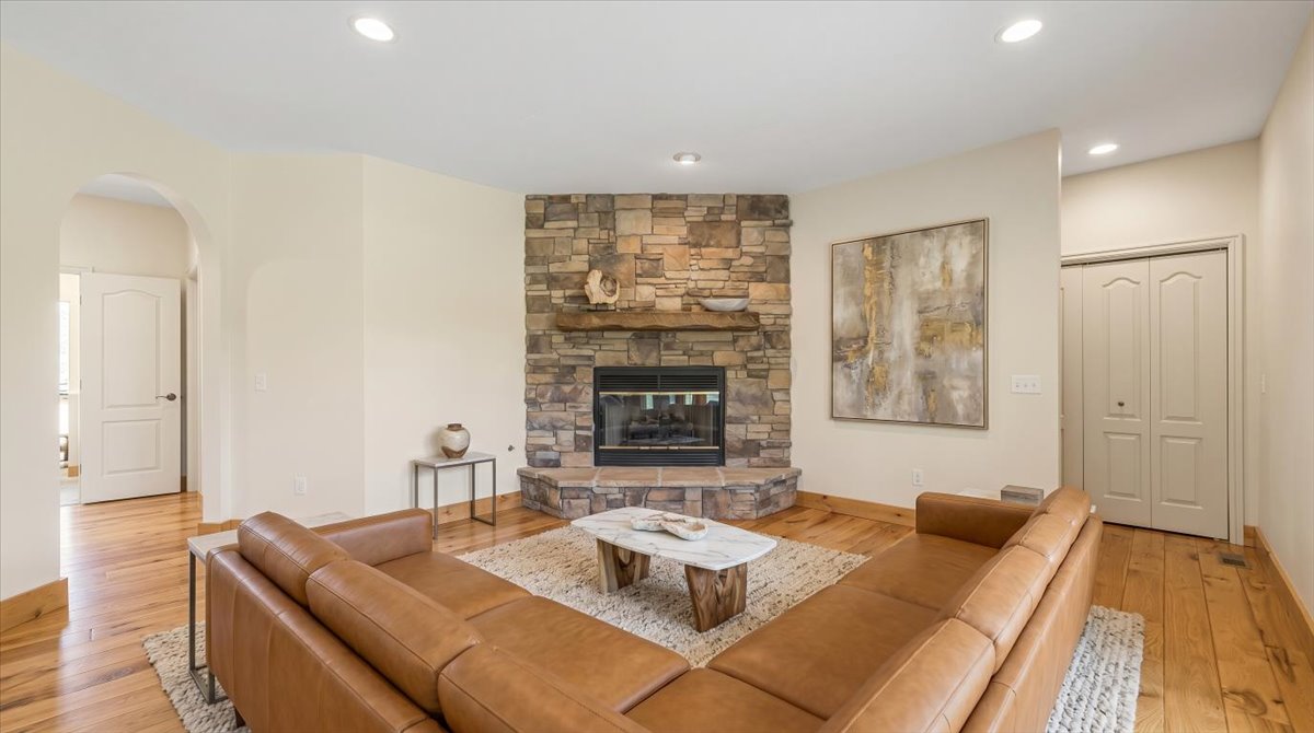 Living area with light wood-style flooring, arched walkways, a fireplace, and recessed lighting