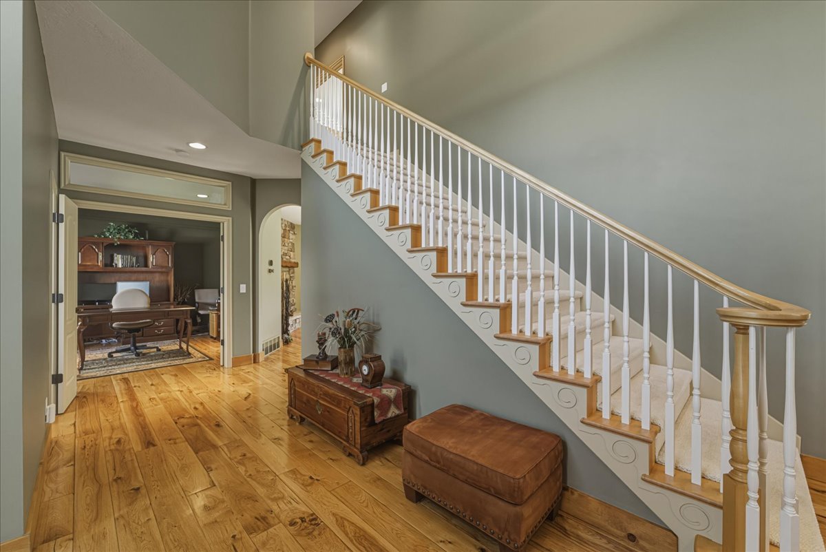 Stairs featuring arched walkways, hardwood / wood-style flooring, recessed lighting, and a high ceiling