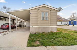 View of side of home featuring an attached carport, concrete driveway, a yard, and a mountain view