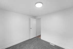 Unfurnished room with baseboards and dark carpet