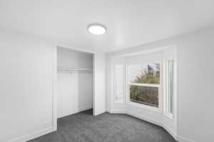 Unfurnished bedroom with dark carpet and a closet