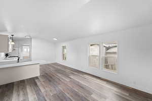 Unfurnished living room featuring vaulted ceiling, dark wood-type flooring, and healthy amount of natural light