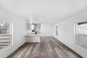 Unfurnished living room with plenty of natural light, dark wood finished floors, vaulted ceiling, and crown molding