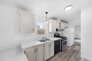 Kitchen featuring gas range, black dishwasher, lofted ceiling, pendant lighting, and dark wood-type flooring