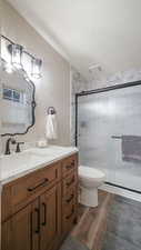 Bathroom featuring a stall shower, vanity, dark wood-style flooring, and a textured ceiling