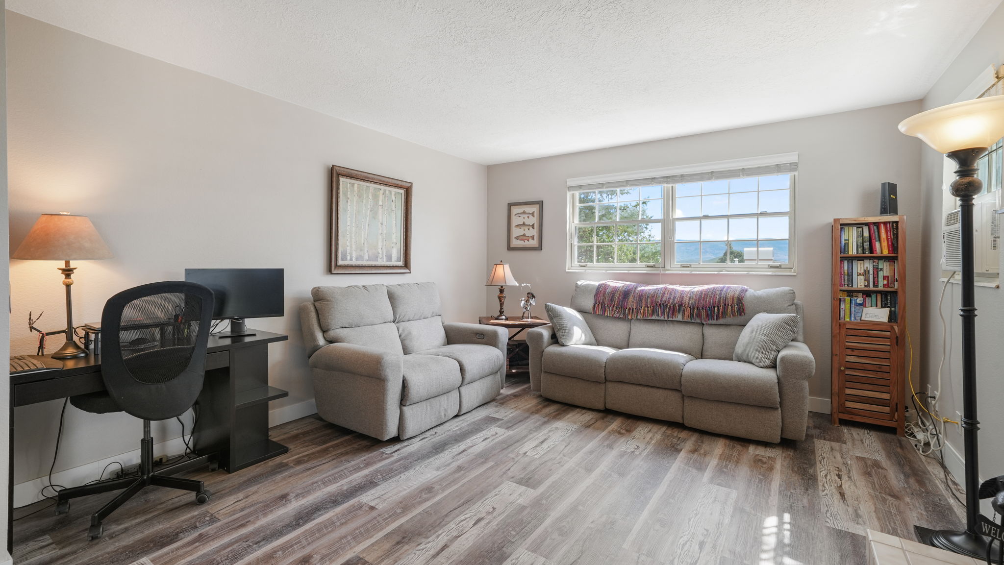 Living area featuring light wood finished floors, a desk, and a textured ceiling