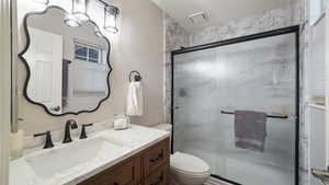 Bathroom featuring vanity, a shower stall, and a textured ceiling