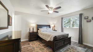 Bedroom with dark wood-type flooring, a ceiling fan, and a textured ceiling