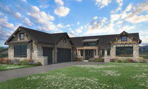 View of front of house with stone siding, asphalt driveway, an attached garage, a front lawn, and a standing seam roof