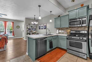 Kitchen featuring a chandelier, stainless steel appliances, light tile patterned floors, a peninsula, and open floor plan