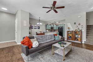 Living area featuring dark wood-style flooring, a ceiling fan, and suspended lighting