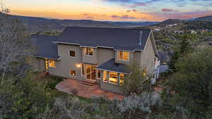 Back of property at dusk featuring stucco siding, a patio, and a mountain view
