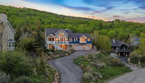 View of front of home with a chimney, asphalt driveway, an attached garage, and a balcony