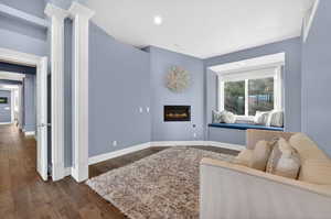 Living area featuring dark wood-style flooring, a glass covered fireplace, and recessed lighting
