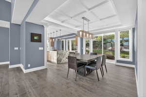 Dining area with coffered ceiling, dark wood-style floors, and suspended lighting
