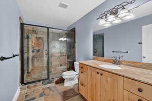 Bathroom with vanity, a marble finish shower, and stone tile floors