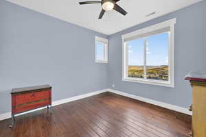Empty room featuring ceiling fan and dark wood-style floors