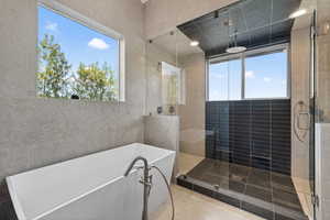 Full bathroom featuring a shower stall, a freestanding tub, and tile walls