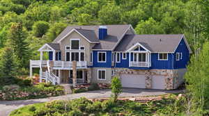 View of front of house featuring an attached garage, a shingled roof, stone siding, and asphalt driveway