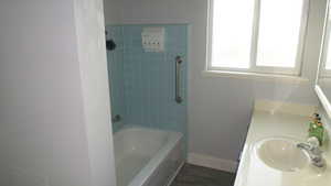 Bathroom featuring vanity,  shower combination, and dark wood-style flooring