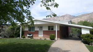 View of front facade featuring an attached carport, brick siding, a porch, and concrete driveway