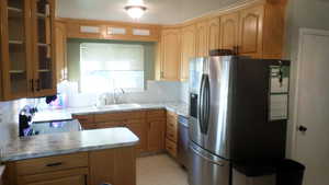 Kitchen with stainless steel appliances, a peninsula, light countertops, glass insert cabinets, and light floors
