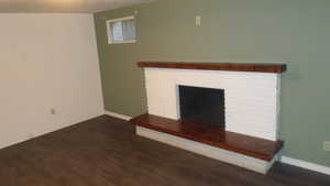 Family room with dark wood-type flooring and a brick fireplace
