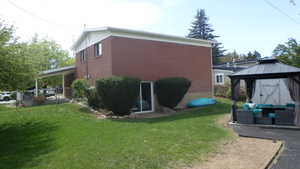 View of side of property with outdoor lounge area, a patio, a gazebo, and brick siding