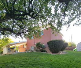 Expansive backyard featuring a lawn, mature trees, and a brick exterior