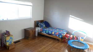 Bedroom with multiple windows and wood finished floors