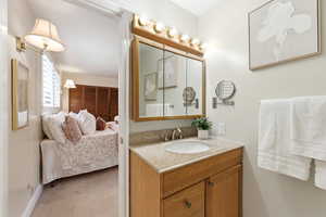 Ensuite bathroom featuring vanity and light colored carpet